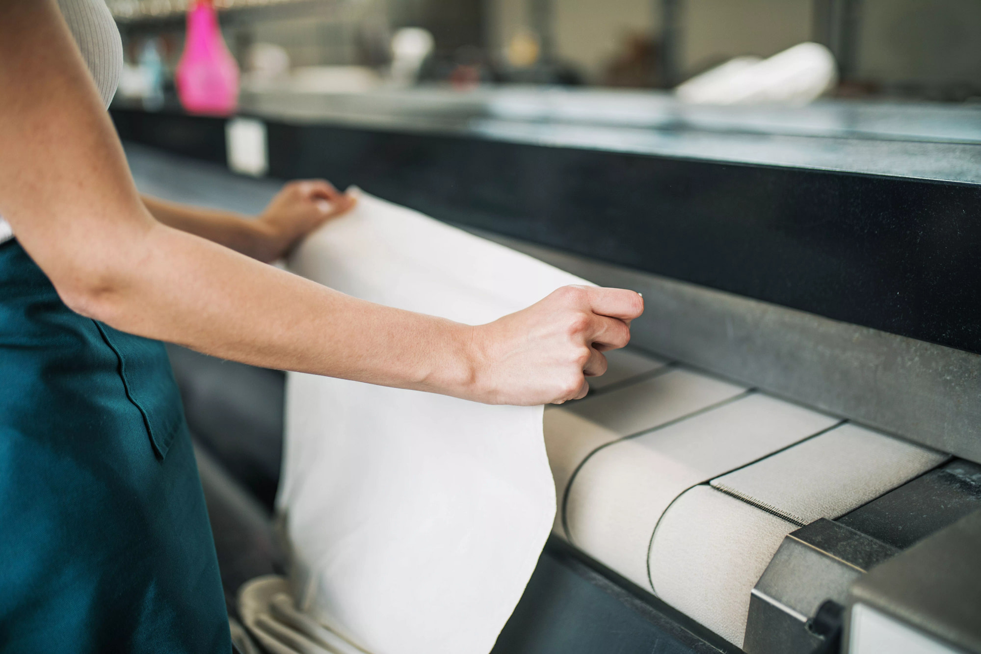 young laundry worker pats linen automatic machine dry cleaners